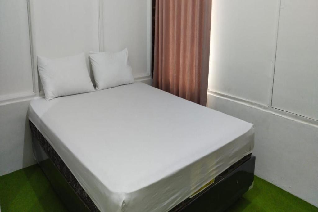 a bed with white sheets and pillows in a room at SPOT ON 92544 Senja Homestay in Balikpapan
