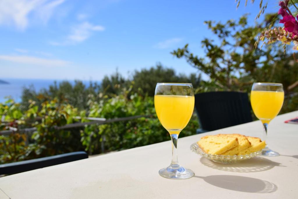 two glasses of orange juice and bread on a table at Perfetto Country House - Myrtos View in Anomeriá