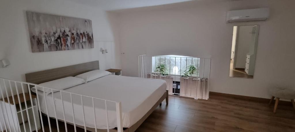a bedroom with a white bed and a mirror at casetta arianna in Brindisi