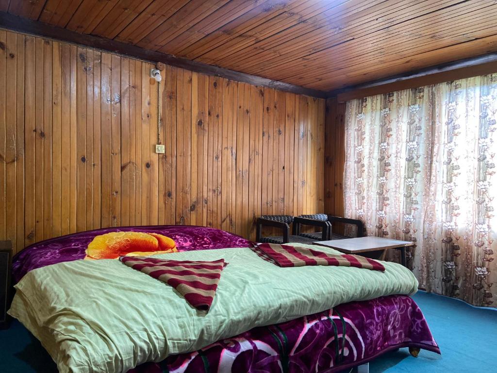 a bedroom with a bed in a room with wooden walls at PK cottage in Pahalgām