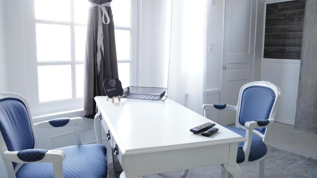 a white desk with a laptop and two chairs at Estudio Central London Consulado in Tijuana