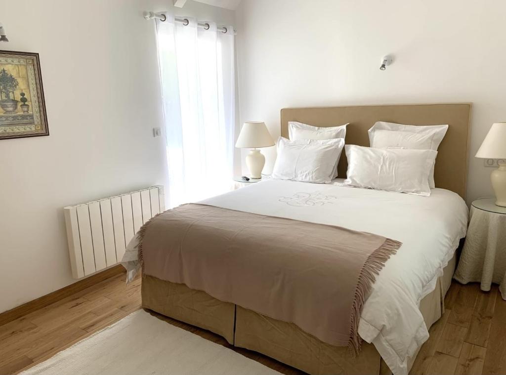 een slaapkamer met een groot wit bed met witte kussens bij Beautiful little house renovated in nature 
