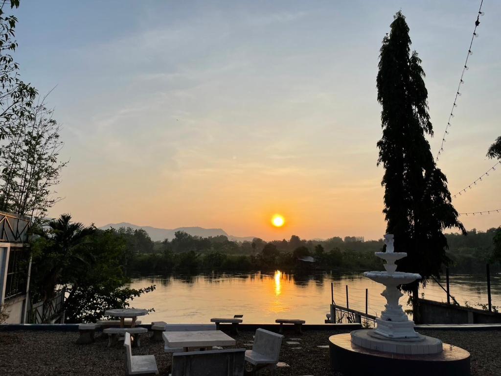 a sunset over a body of water with a fountain at Tara Kan Resort in Ban Nong Hin