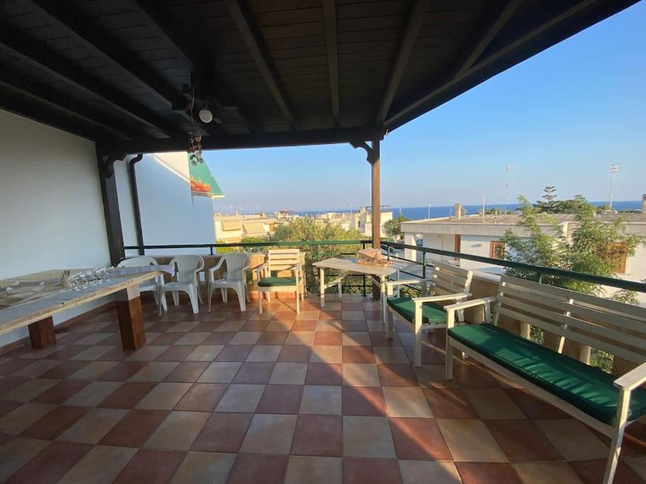einen Balkon mit Bänken und Tischen und Meerblick in der Unterkunft Villa Chia’ in Santa Cesarea Terme