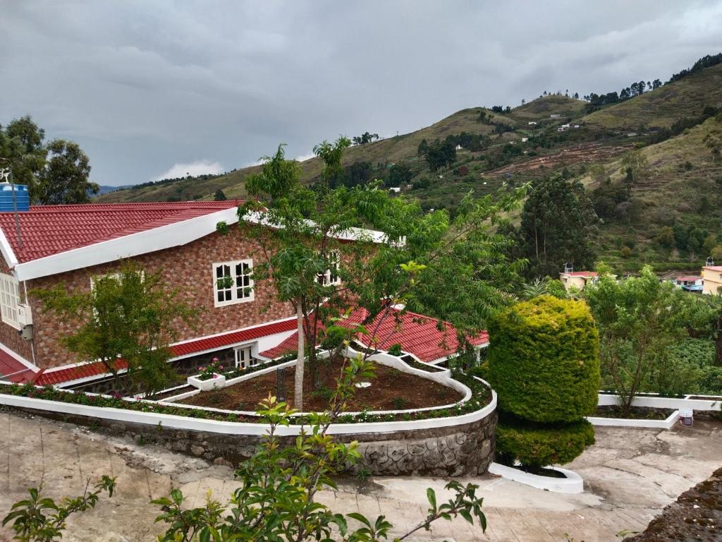 une maison avec un jardin en face d'une montagne dans l'établissement INN THE MOUNTAIN'S, à Kodaikānāl