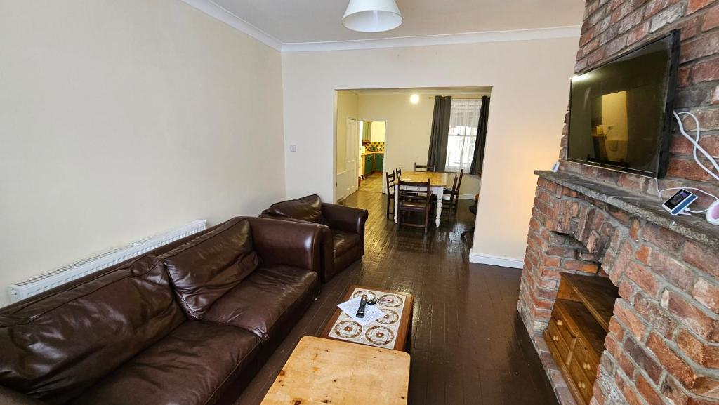 a living room with a couch and a brick fireplace at Sherwood Terrace 3 Bedroom 1 Double Bed 4 Single Beds Entire Property Contractors Welcome in Boston