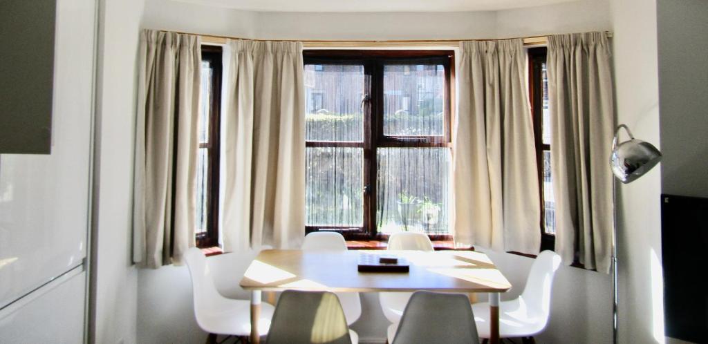 a dining room with a table and chairs and a window at Lovely 3 bed ground floor flat with free parking in Swanage