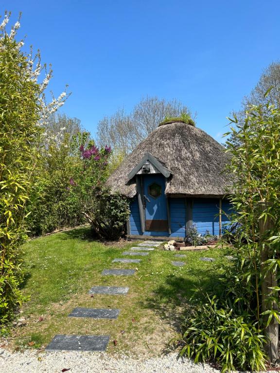 une maison bleue avec un toit de chaume et un chemin dans l'établissement Aux murmures de la nature, à Honfleur