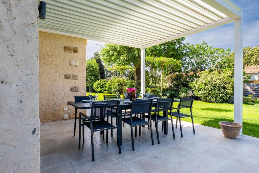 patio ze stołem i krzesłami pod pergolą w obiekcie Calm family house with swimming pool w mieście Antibes