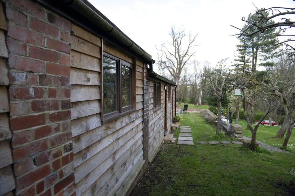 una casa de ladrillo con ventanas en un lateral en a quirky garden building in an orchard, en Ryton