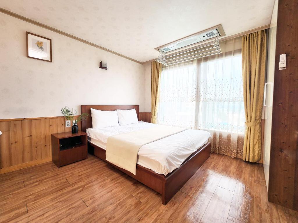 Un dormitorio con una cama grande y una ventana en Jungmun Haesung Parktel, en Seogwipo