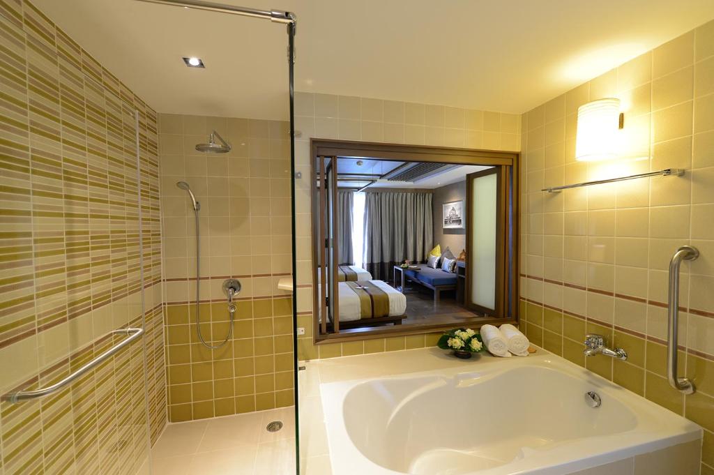 A bathroom with a corner bathtub, separate glass-enclosed shower, and bedroom-facing mirror.