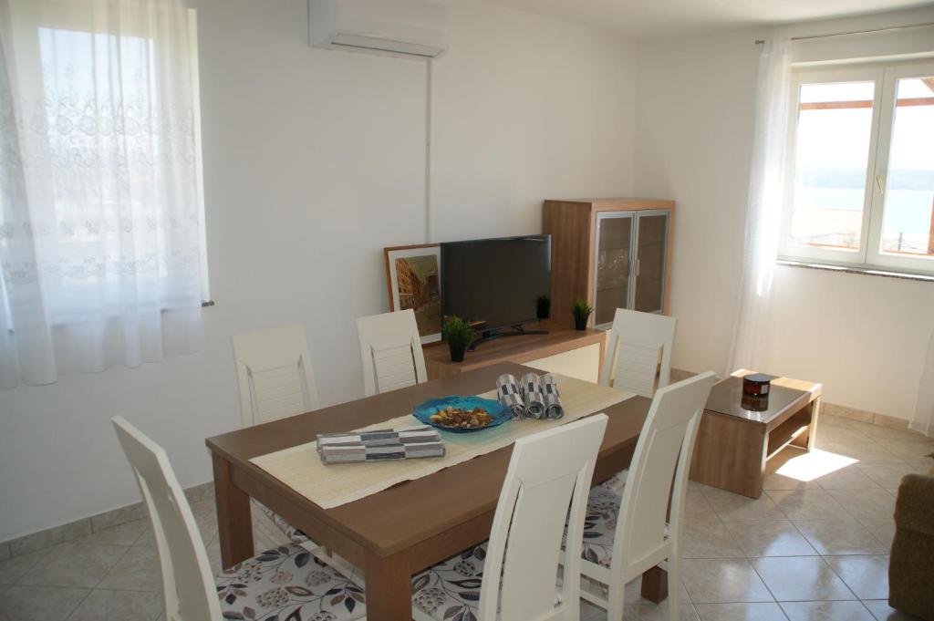 a dining room with a wooden table and white chairs at Apartments Brko in Maslenica