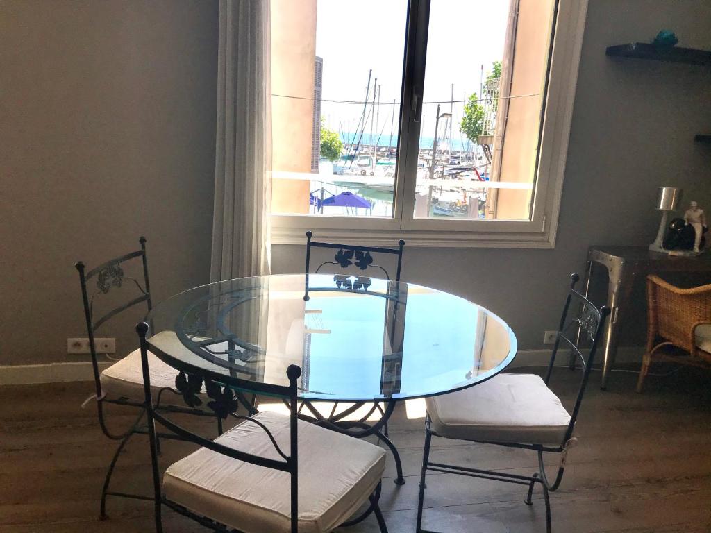 une table et des chaises en verre dans une chambre avec fenêtre dans l'établissement Appartement entier 3 pièces face au port, à Vallauris