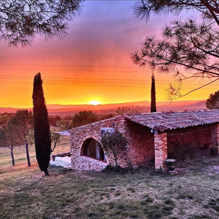 un edificio de piedra en un campo con una puesta de sol en el fondo en Lodge - Le Clos Devançon, en Gréoux-les-Bains