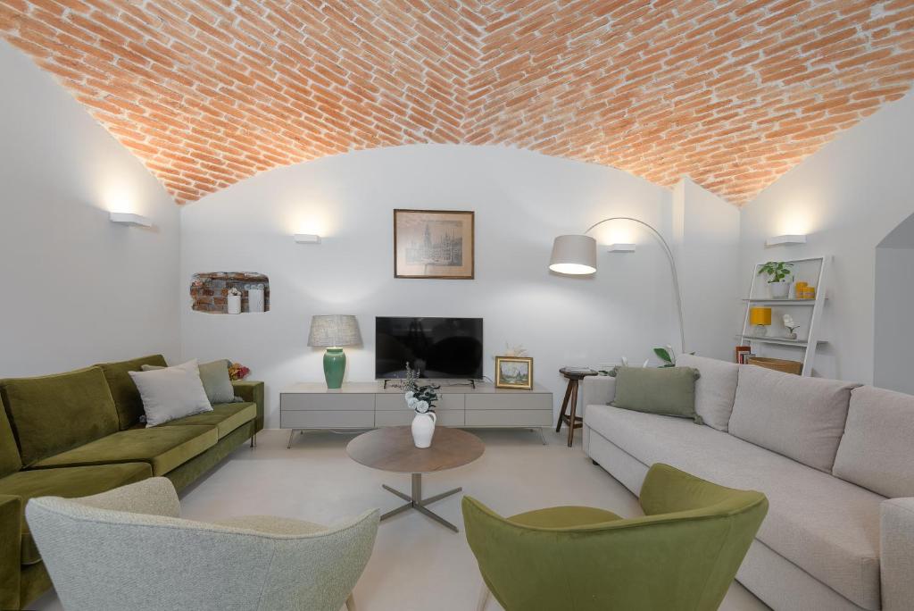 uma sala de estar com um sofá e cadeiras e uma televisão em Exklusiv: Historisches Apartment mit Deckengewölbe em Munique