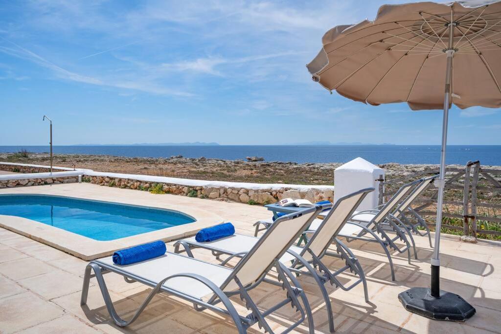 a group of chairs and an umbrella next to a swimming pool at Sa Calma in Cala Blanca