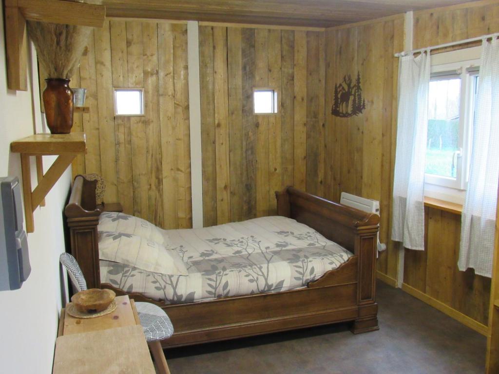 a bedroom with a bed in a room with wooden walls at LA BAROUD' ER in Voillecomte