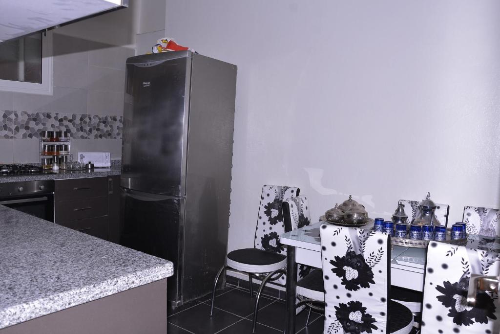 a kitchen with a black refrigerator and a table and chairs at Chez zoubida in Meknès