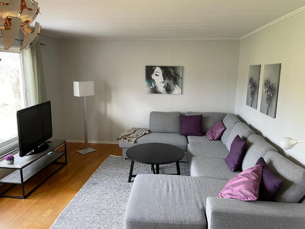 a living room with a gray couch and purple pillows at Familjevänligt hus nära Isaberg! in Hestra