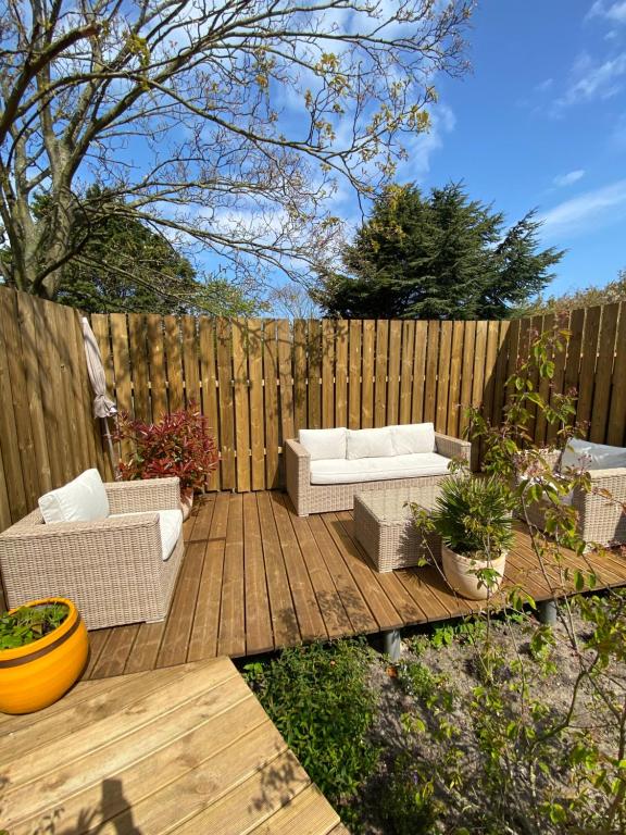 a patio with two couches and a wooden fence at Le jardin secret in Sangatte