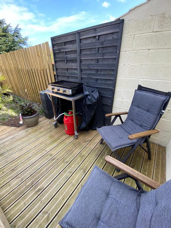 a grill and two chairs on a wooden deck at Le jardin secret in Sangatte