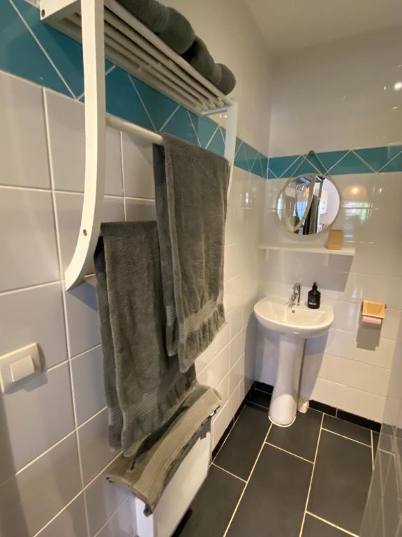 a bathroom with a sink and a toilet and towels at Le jardin secret in Sangatte