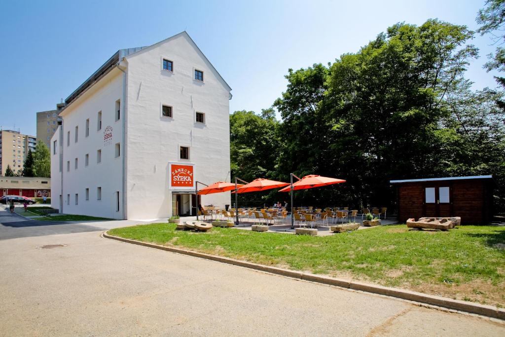 un bâtiment avec des tables et des parasols devant lui dans l'établissement Hotel Zámecká Sýpka, à Blansko