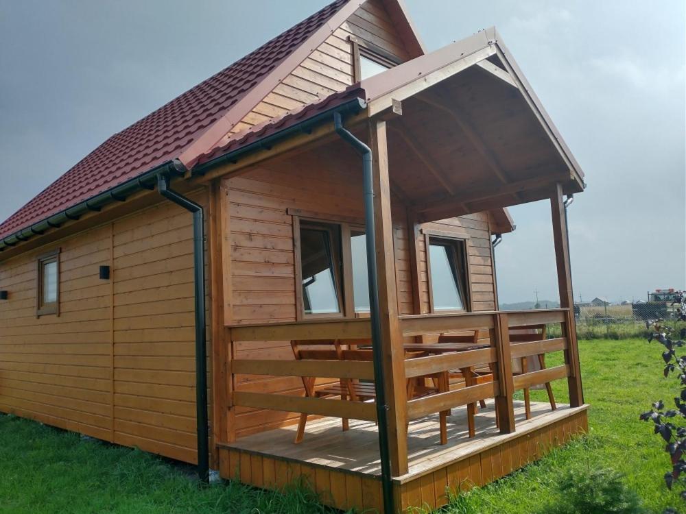 a wooden cabin with a large deck in a field at Domek na wyłączność LAWENDA in Jezierzany