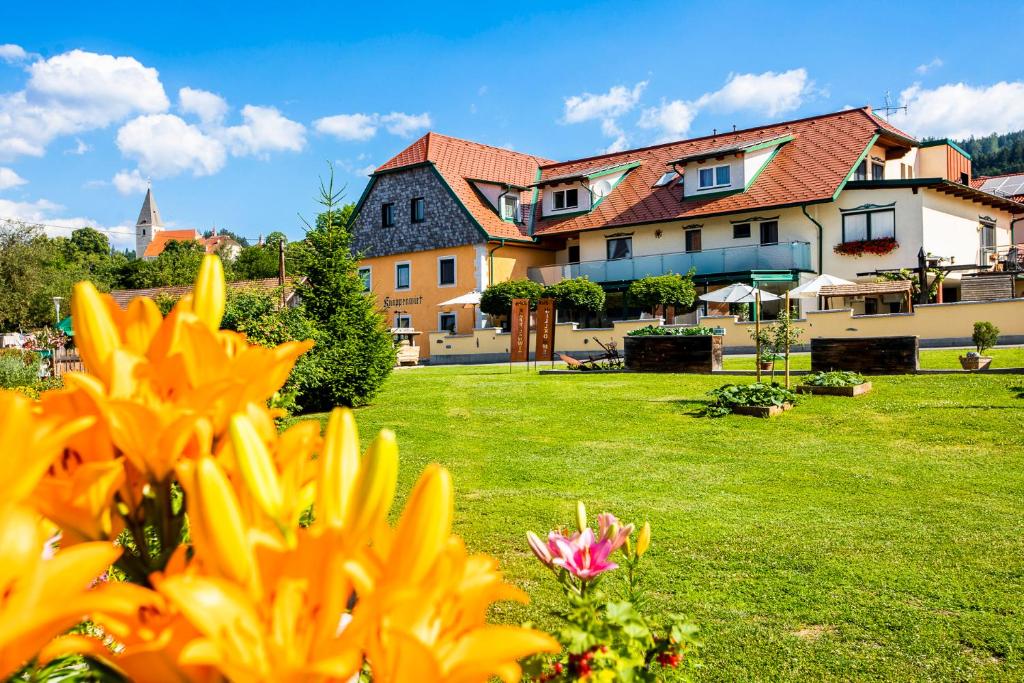 eine Gruppe von Gebäuden auf einem grünen Feld mit Blumen in der Unterkunft Gasthof Knappenwirt in Mariahof