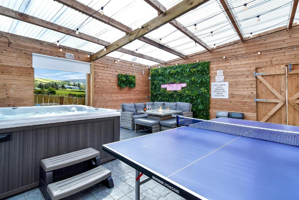 patio con mesa de ping pong y bañera de hidromasaje en Glenside Abbey 'Sleeping 7 guests', en Buncrana