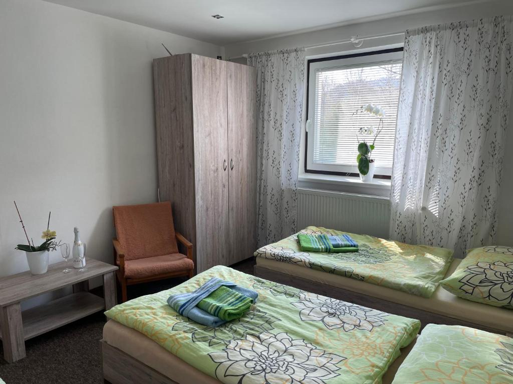 a room with two beds and a chair and a window at Apartmány pri Zvonici in Oravský Podzámok