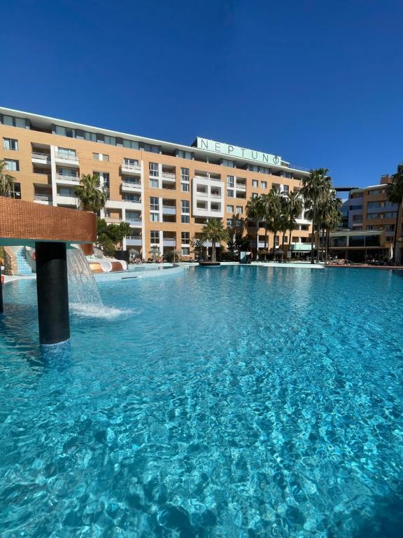 una grande piscina d'acqua di fronte a un edificio di Hotel Neptuno by ON GROUP a Roquetas de Mar