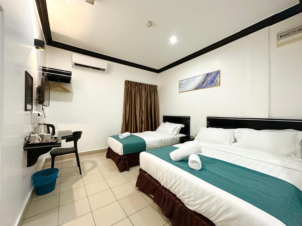 a hotel room with two beds and a desk at Hotel Tourist City Centre by HotSpot Essential in Kota Kinabalu