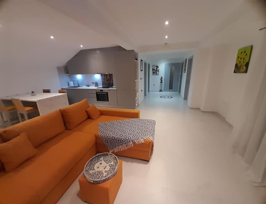 uma sala de estar com um sofá laranja e uma cozinha em Jan-Air em Ilinden