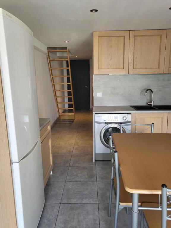 a kitchen with a table and a stove and a dishwasher at Appart 30 m2 cosy 2 personnes 1 grande chambre en mezzanine in Saint-Mitre-les-Remparts