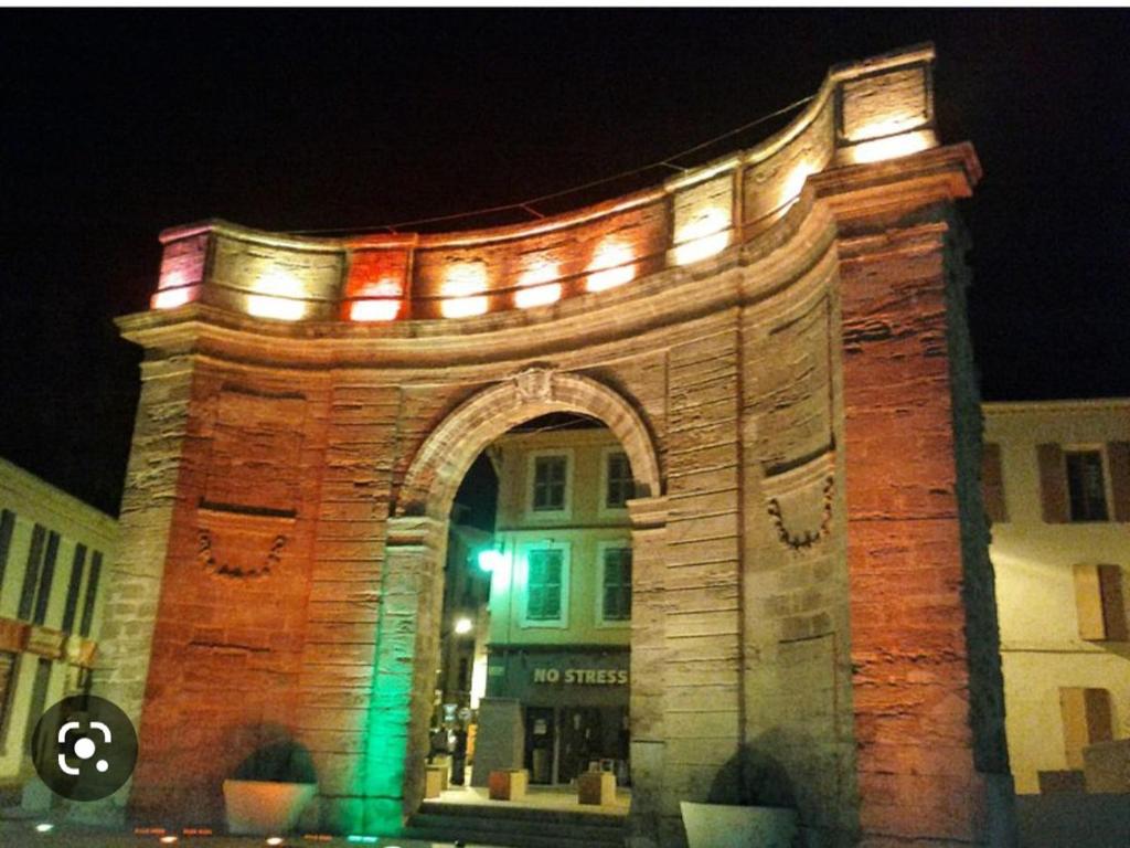 a large brick building with an arch at night at Appart 30 m2 cosy 2 personnes 1 grande chambre en mezzanine in Saint-Mitre-les-Remparts