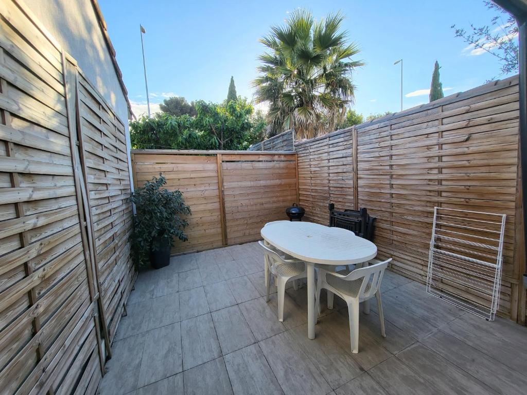 a table and chairs on a patio with a fence at Appart 30 m2 cosy 2 personnes 1 grande chambre en mezzanine in Saint-Mitre-les-Remparts