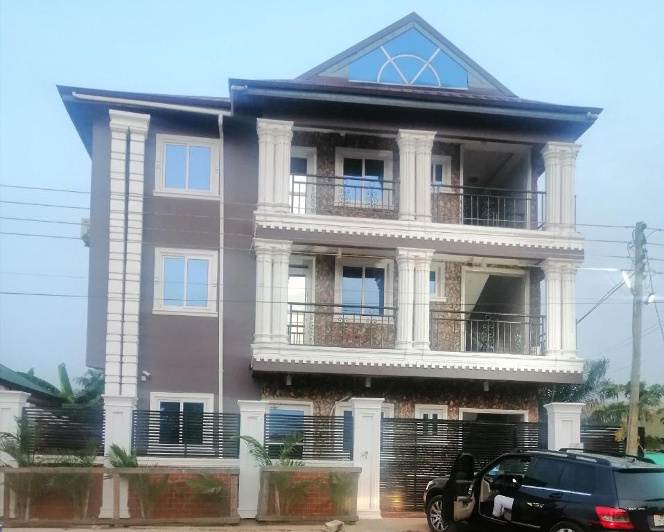 a large house with a balcony and a car parked in front at Terra Santa Lodgings in Accra