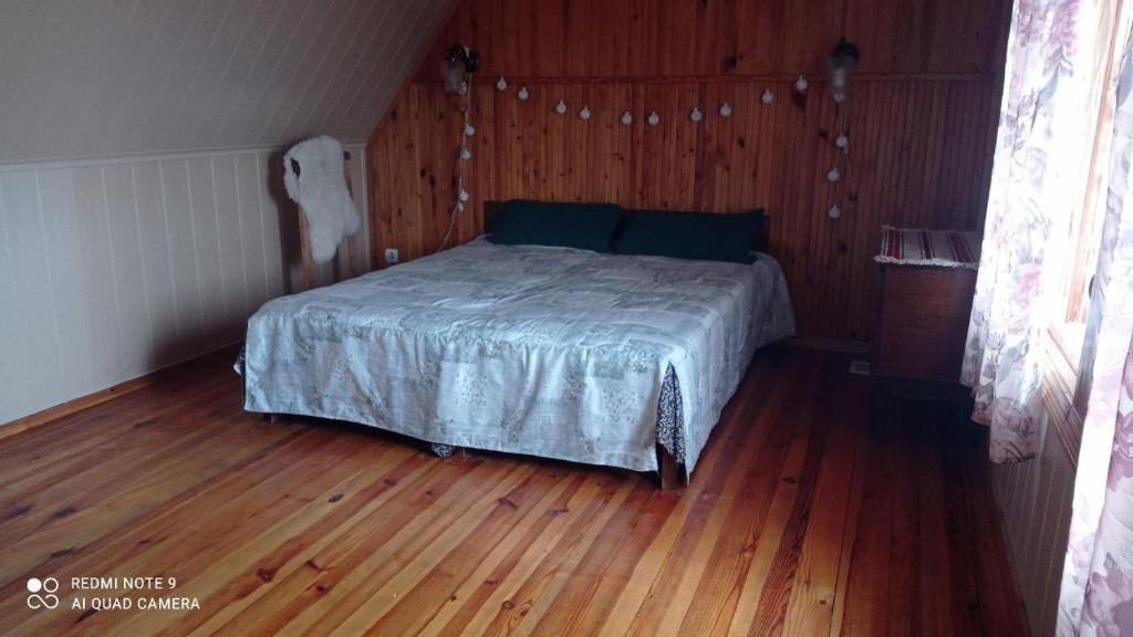 ein Schlafzimmer mit einem Bett in einem Holzboden in der Unterkunft Садиба Живиця in Kozlin