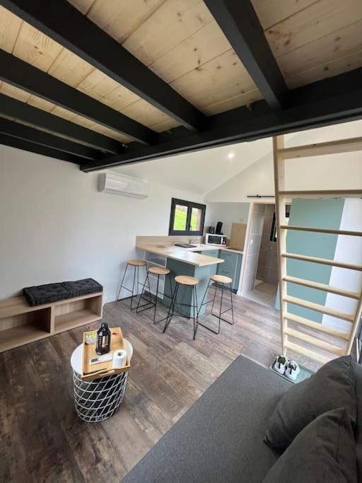 a living room with a loft with a table and chairs at Tiny House L’œil des Dômes in Saint-Pierre-le-Chastel