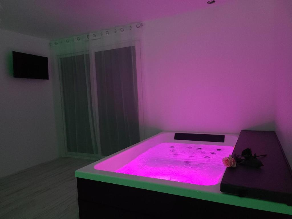 a room with a hot tub with pink lighting at L'escale Romanesque in Ozeville