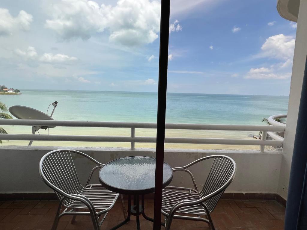 einen Tisch und Stühle auf einem Balkon mit Meerblick in der Unterkunft Tanjung Tuan Regency Port Dickson Pool opened in Port Dickson