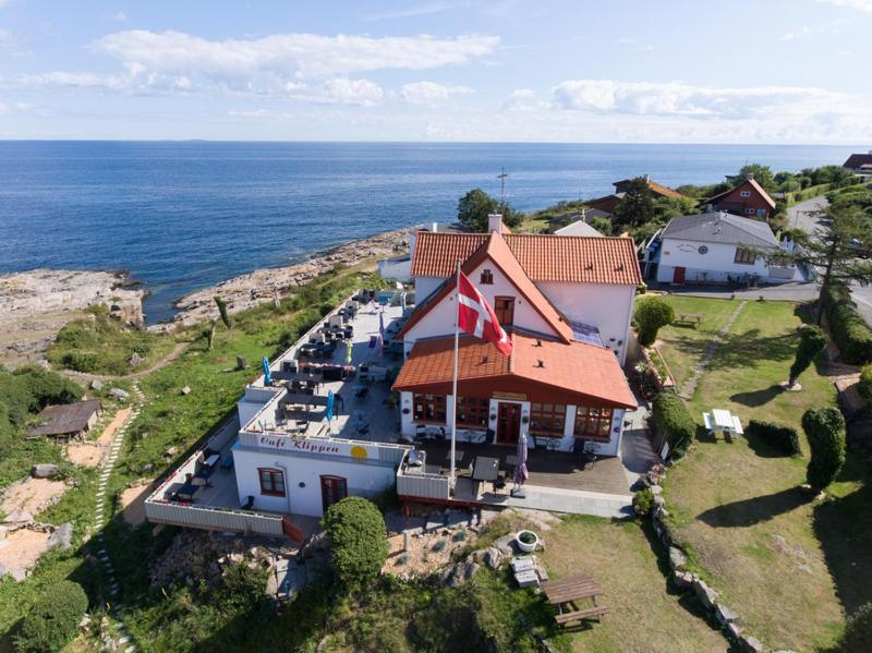 a house with a flag on top of it next to the ocean at Hotel Klippen in Gudhjem