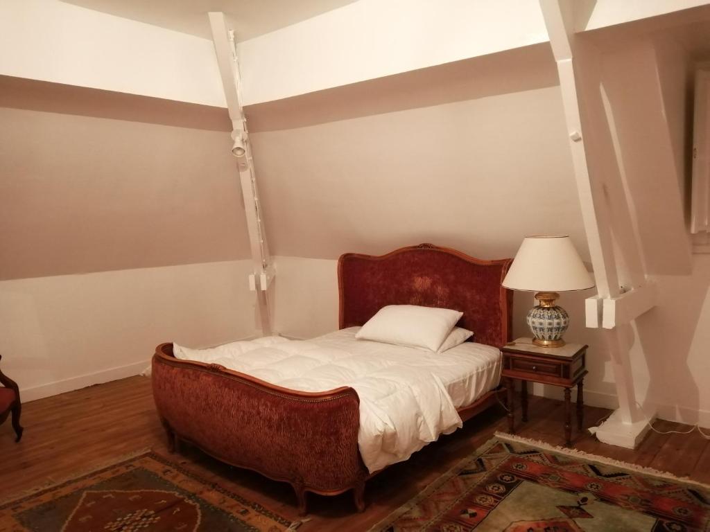 een slaapkamer met een bed en een tafel met een lamp bij Villa Biscondau in Oloron-Sainte-Marie