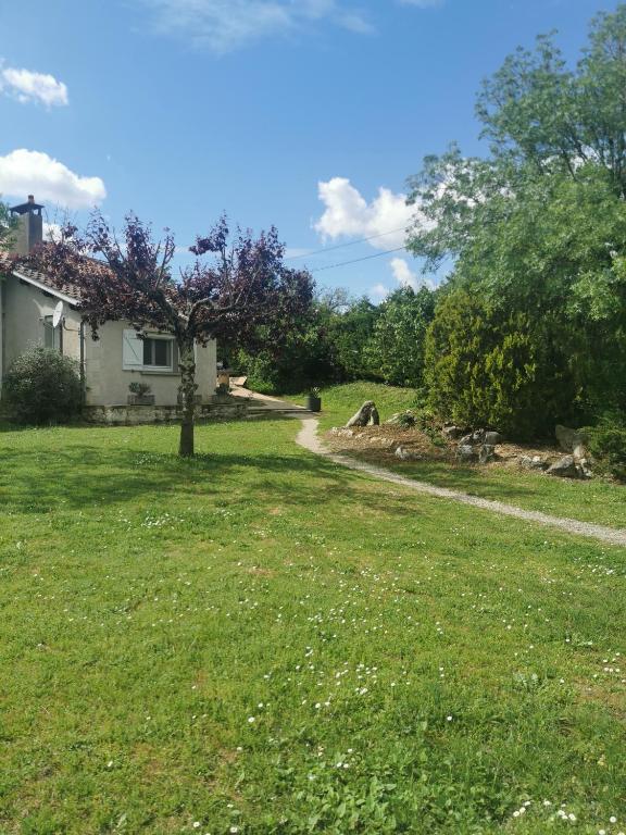 une cour avec une maison et un arbre dans l'herbe dans l'établissement Hébergement, à Montpezat-de-Quercy