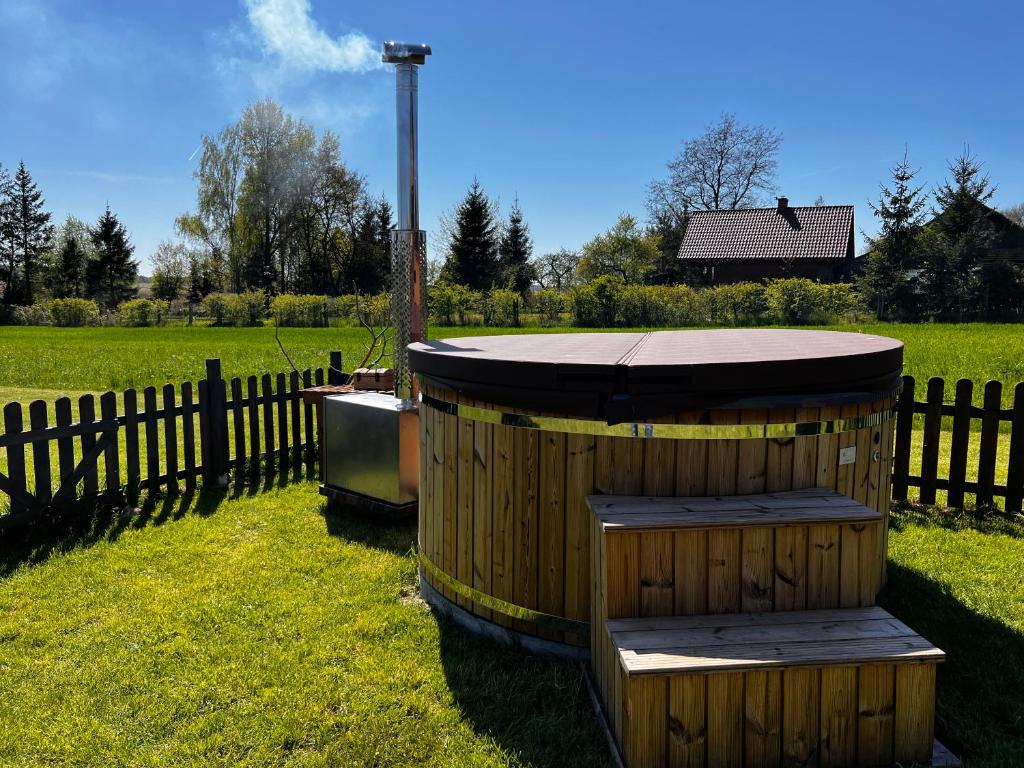 una bañera de madera sentada en el césped junto a una valla en Świerkowy Domek pod Aniołem, en Łapy