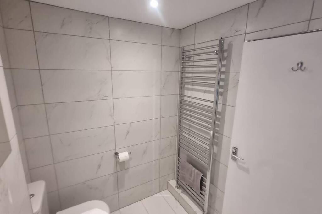 uma casa de banho branca com um chuveiro e um WC. em Spacious self contained flat in superb location em Lymington