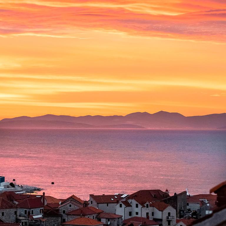 a sunset over the ocean with houses and buildings at Apartment Zen u Postira in Postira