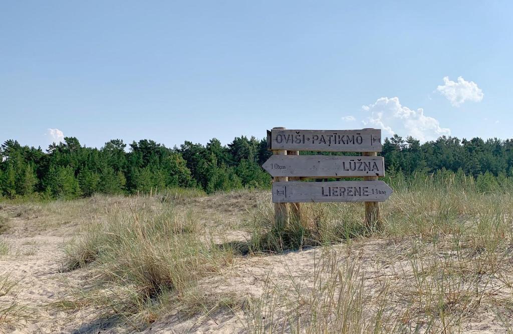 een houten bord in het midden van een veld bij Kadiķi in Ventspils